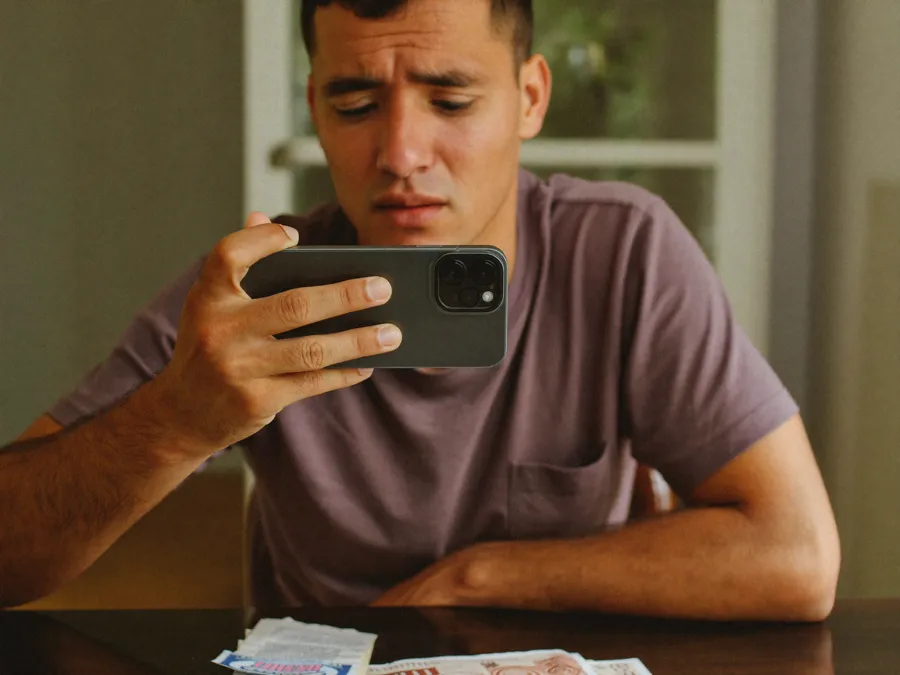 Pessoa preocupada olhando o celular ao descobrir o nome negativado